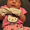 newborn, baby, sleeping, infant, portrait, indoors, pink_clothing, hello_kitty, bow, blanket, sitting, lap, chair, cozy, cute, peaceful, face, closed_eyes, family_photo, casual_snapshot