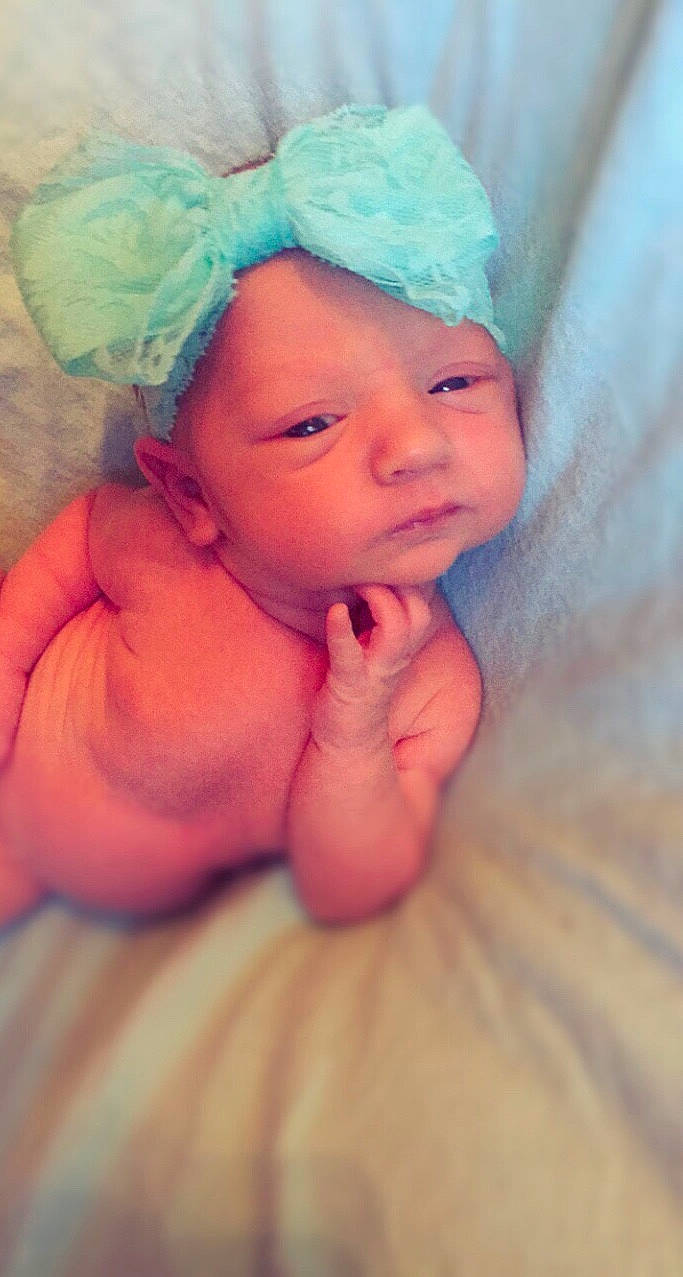 Alaina is registered to the contest to win money with this photo: cheek, child, close_up, eye, face, finger, girl, hair_accessory, hand, happiness, headgear, infant, iris, lip, person, pink, skin, smile, toddler