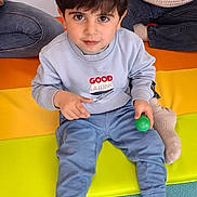 Gabriel participe au concours pour gagner de l'argent avec cette photo : adult, blue_pants, boy, casual_clothing, child, colorful_mat, cute, floor, footwear, green, indoor, jeans, looking_up, person, playtime, sitting, sock, sweatshirt, toy, young