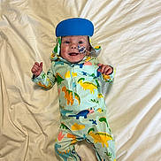 Jude joined the competition — help win amazing prizes! baby, infant, smiling, face, blue_hat, dinosaur_onesie, medical_tube, bed, white_bedspread, child, cute, lying_down, happy, young_child, indoors, person, apparel, foot, hand, headwear