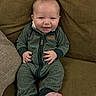 baby, child, infant, smiling, happy, portrait, sitting, couch, cushion, indoor, home, clothing, green_outfit, jumpsuit, bare_feet, face, hands, cozy, photography, adorable