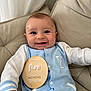 Anthony joined the competition — help win amazing prizes! baby, infant, smile, blue_clothing, white_clothing, milestone_sign, wooden_sign, cushion, beige_chair, indoor, portrait, happy, child, sitting, cute, person, closeup, young_child, fabric, buttoned_outfit
