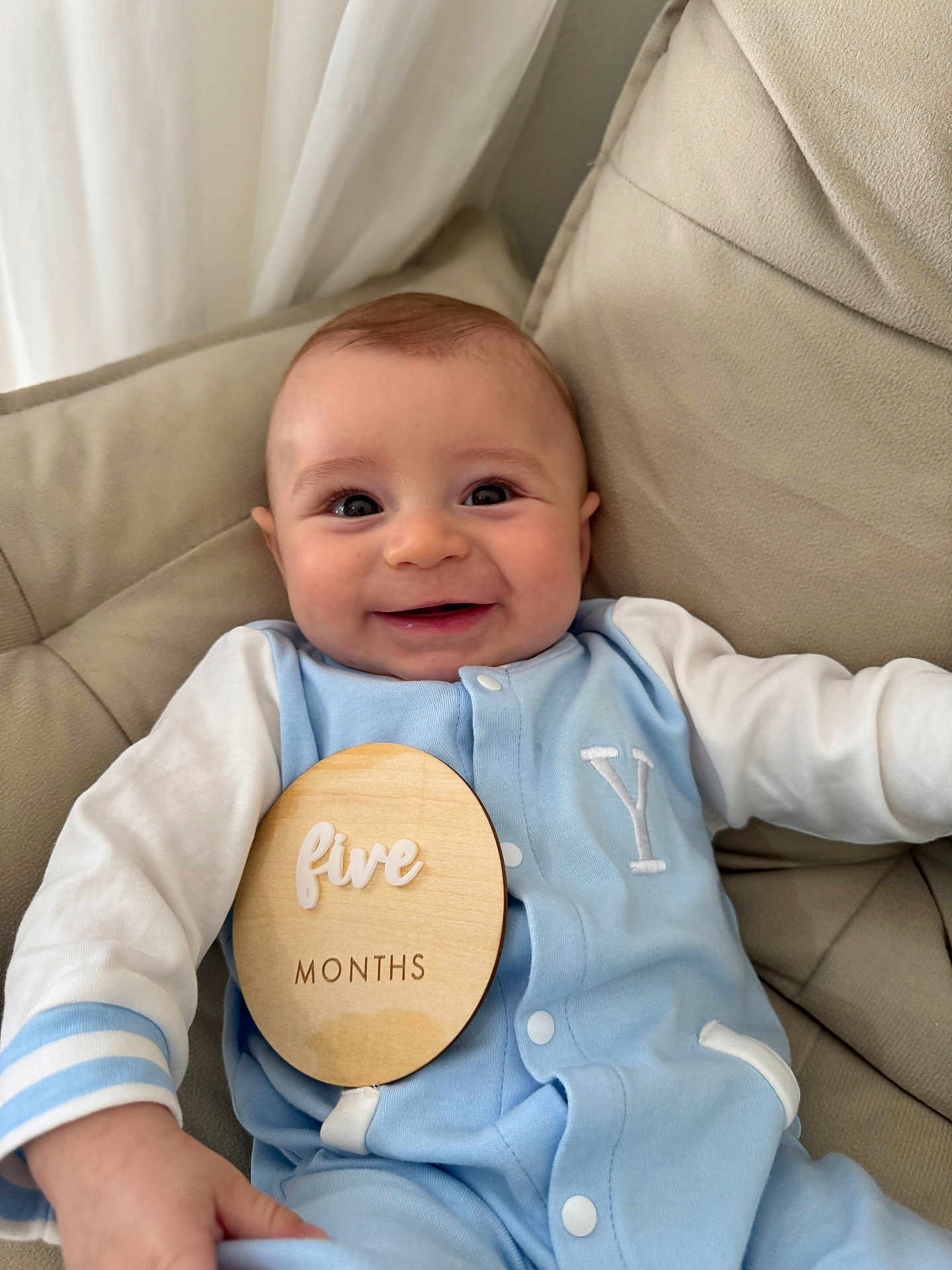 Anthony joined the competition — help win amazing prizes! baby, infant, smile, blue_clothing, white_clothing, milestone_sign, wooden_sign, cushion, beige_chair, indoor, portrait, happy, child, sitting, cute, person, closeup, young_child, fabric, buttoned_outfit