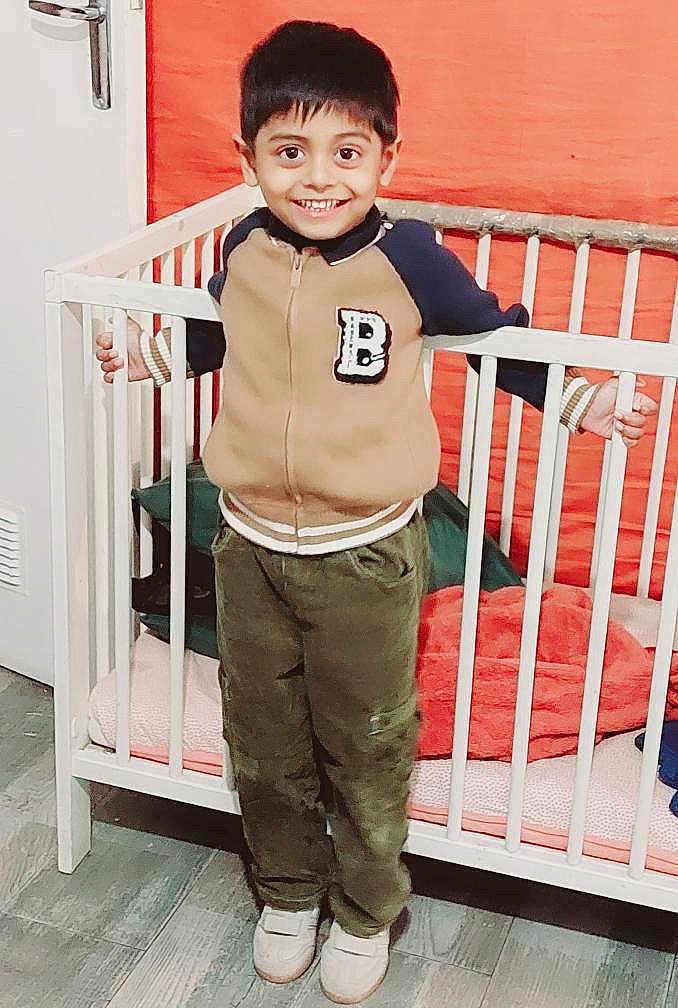 Maruthy participe au concours pour gagner de l'argent avec cette photo : bed, boy, casual_clothing, child, cozy, crib, furniture, grip, happy, indoors, jacket, orange_wall, pants, person, playful, shoes, smiling, standing, wooden_floor, young