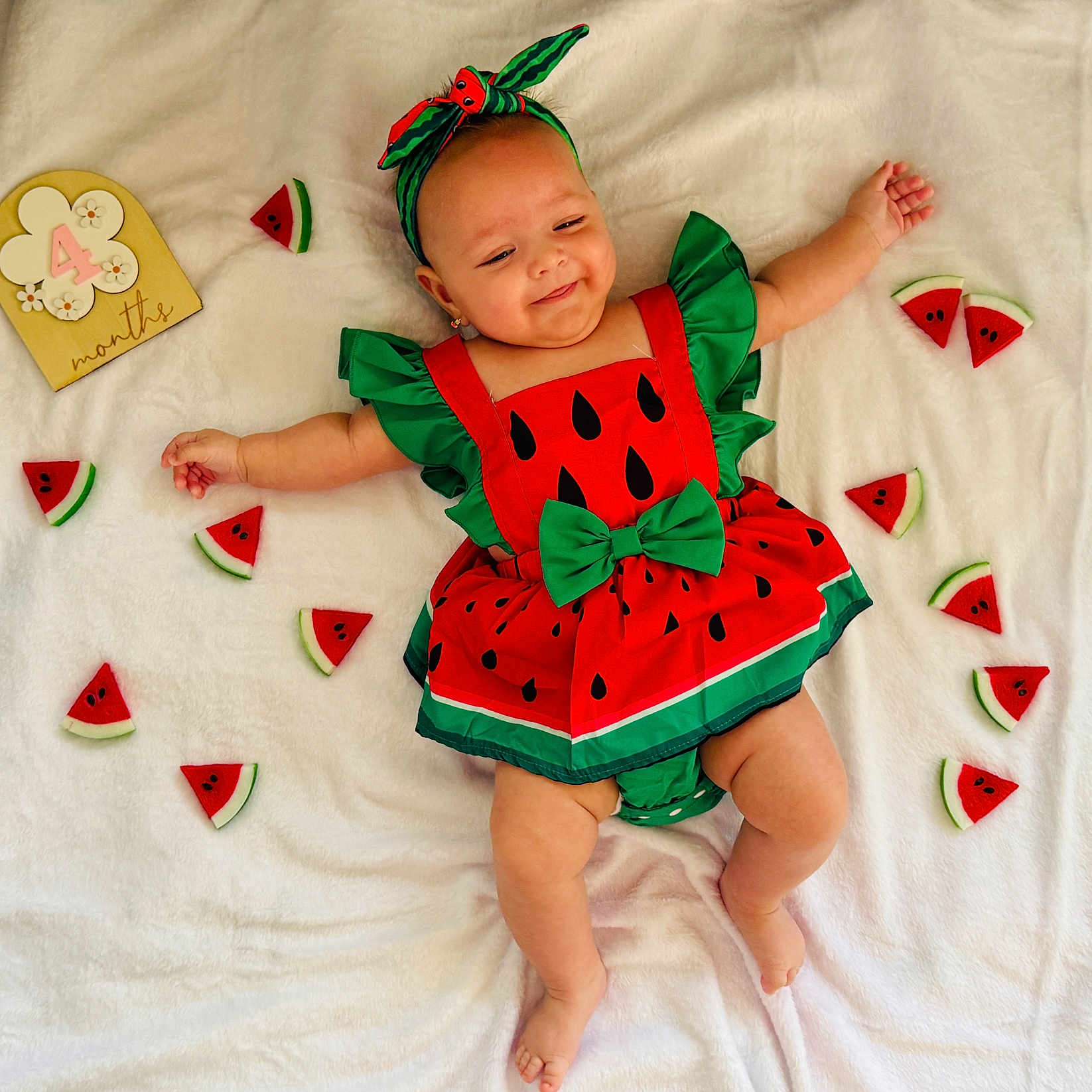 Bessie joined the competition — help win amazing prizes! accessory, arms_spread, baby, blanket, celebration, child, cute, four_months, happy, headband, indoor, infant, legs_bare, lying_down, patterned_clothing, portrait, red_green, smiling, soft_toy, watermelon_outfit