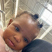 Loyalty is registered to the contest to win money with this photo: baby, child, curly_hair, face, portrait, indoor, person, cute, expression, shoulder, clothing, pink, black, hair_buns, head, looking, closeup, young, infant, toddler