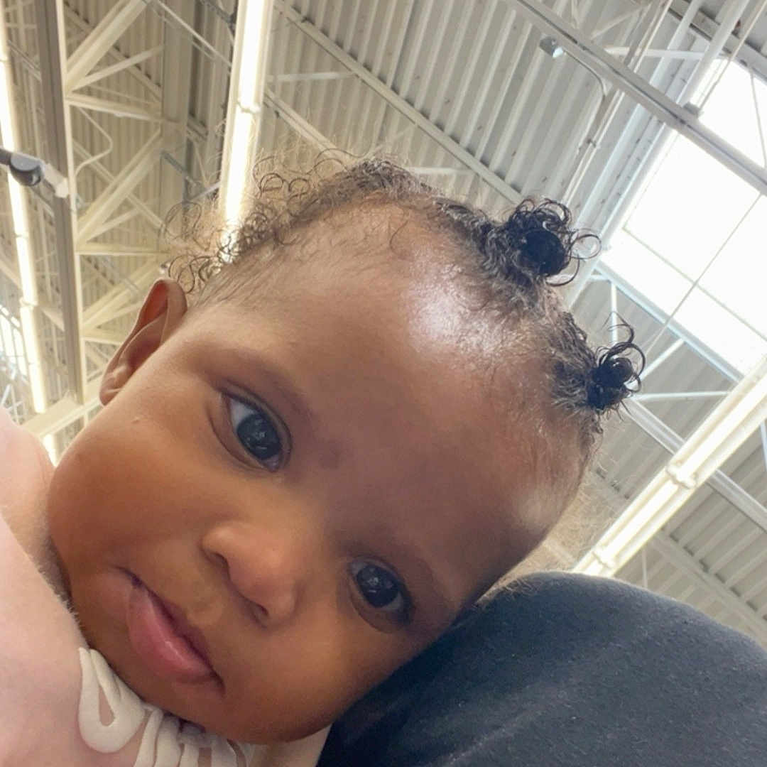 Loyalty is registered to the contest to win money with this photo: baby, child, curly_hair, face, portrait, indoor, person, cute, expression, shoulder, clothing, pink, black, hair_buns, head, looking, closeup, young, infant, toddler