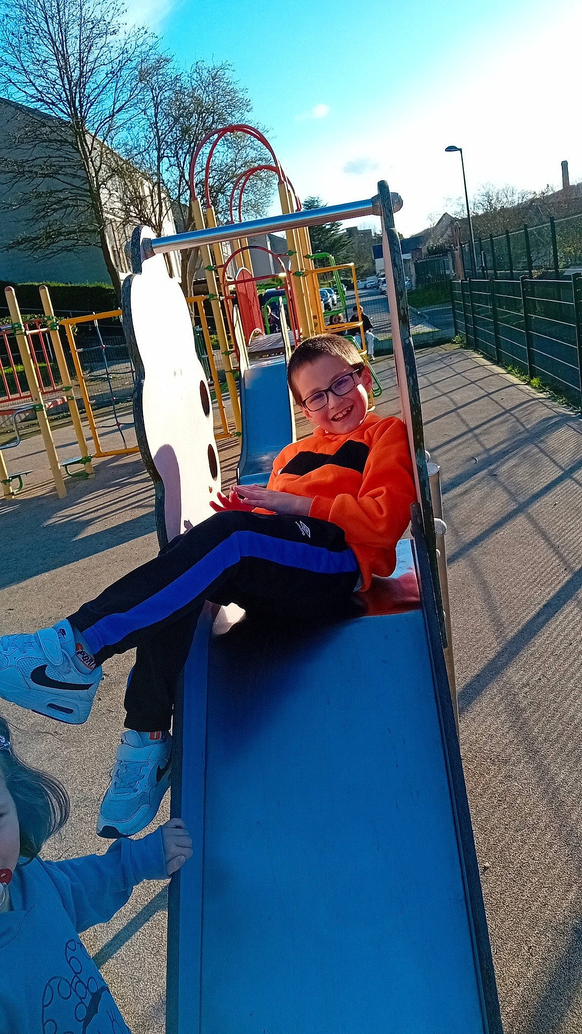 Mathias participe au concours pour gagner de l'argent avec cette photo : blue, chute, city, electric_blue, fence, fun, grass, joy, leisure, nonbuilding_structure, outdoor_play_equipment, person, play, playground, playground_slide, recreation, sitting, sky, swing, toddler