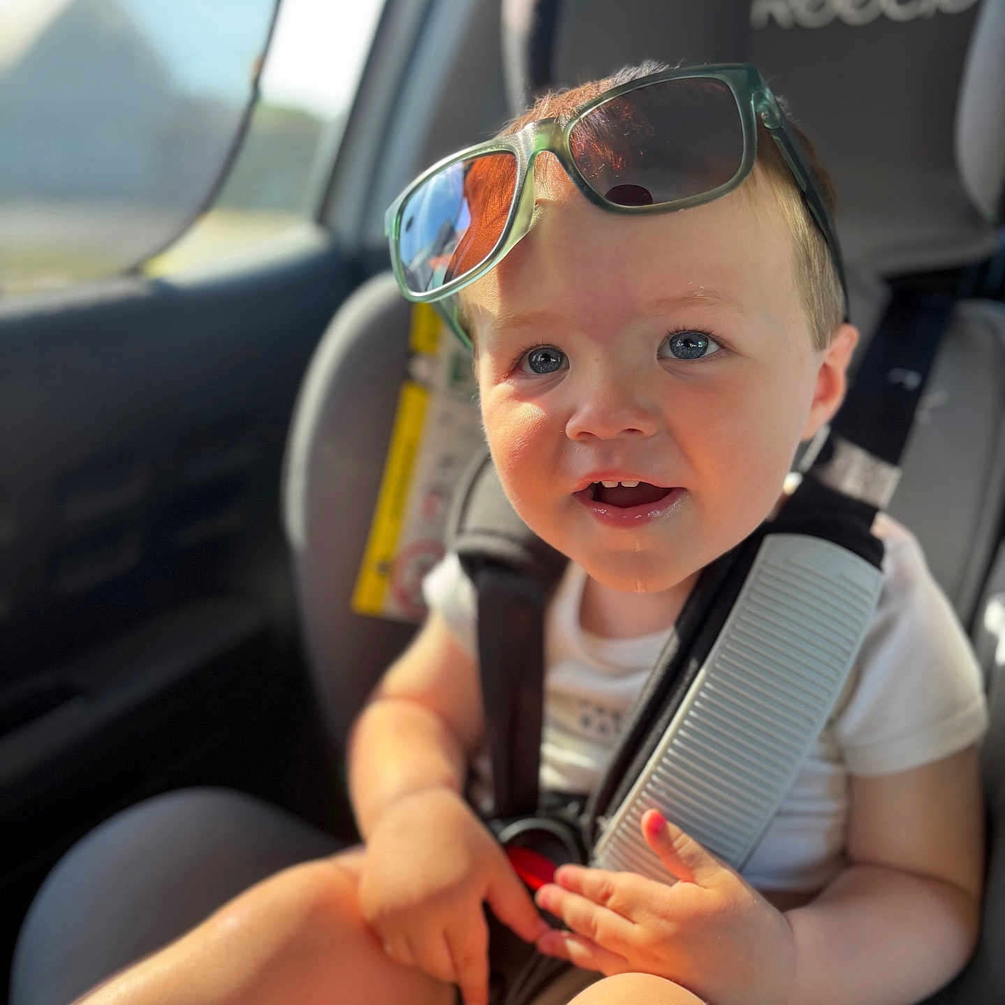 Jules participe au concours pour gagner de l'argent avec cette photo : baby, blue_eyes, car_interior, car_seat, casual_clothing, child, closeup, cute, daylight, happy, infant, portrait, safety_harness, seatbelt, sitting, smiling, sunglasses, sunlight, toddler, young_child