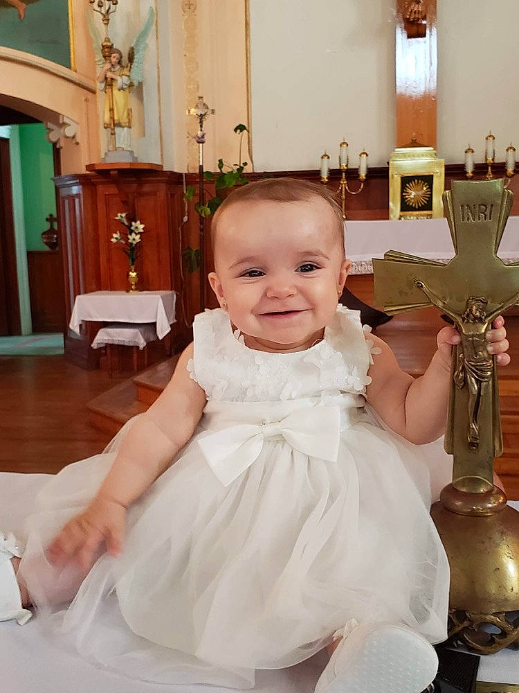 Malia is registered to the contest to win money with this photo: baby, baby_toddler_clothing, ceremony, chair, child, dress, event, flooring, formal_wear, fun, hairstyle, happy, jewellery, joy, person, room, sitting, smile, table, toddler