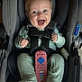 Peyton joined the competition — help win amazing prizes! baby, infant, child, smiling, happy, car_seat, harness, seat_belt, remote_control, toy, onesie, green_clothing, socks, blue_eyes, headrest, buckle, portrait, closeup, indoor, joyful