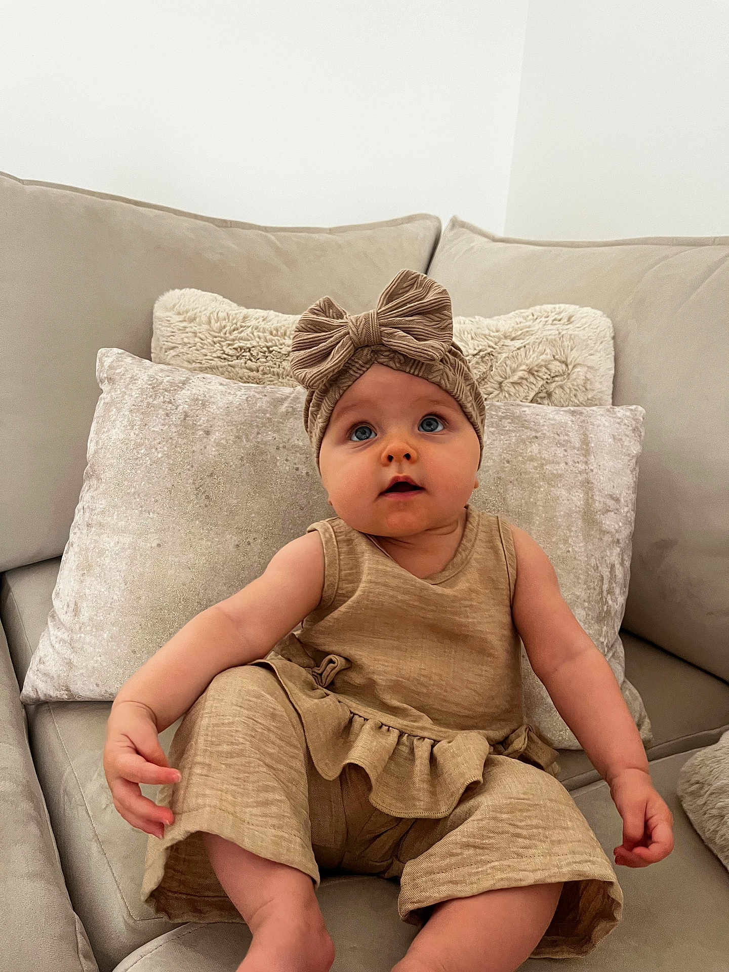 Novella joined the competition — help win amazing prizes! baby, child, infant, couch, pillows, headband, bow, beige, clothing, sitting, indoor, cute, soft, plush, portrait, person, young, curious, comfortable, home