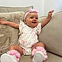 Novella is registered to the contest to win money with this photo: baby, child, infant, girl, pink_bow, headband, dress, pink_leg_warmers, sitting, couch, beige_couch, smiling, happy, arms_outstretched, indoor, furniture, plush_blanket, white_dress, footwear, portrait
