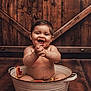 baby, bare_chest, bath, bucket, child, citrus, grapefruit, happy, indoor, laughing, orange_slices, playful, portrait, rustic, smiling, toddler, tub, water, wooden_background, wooden_floor