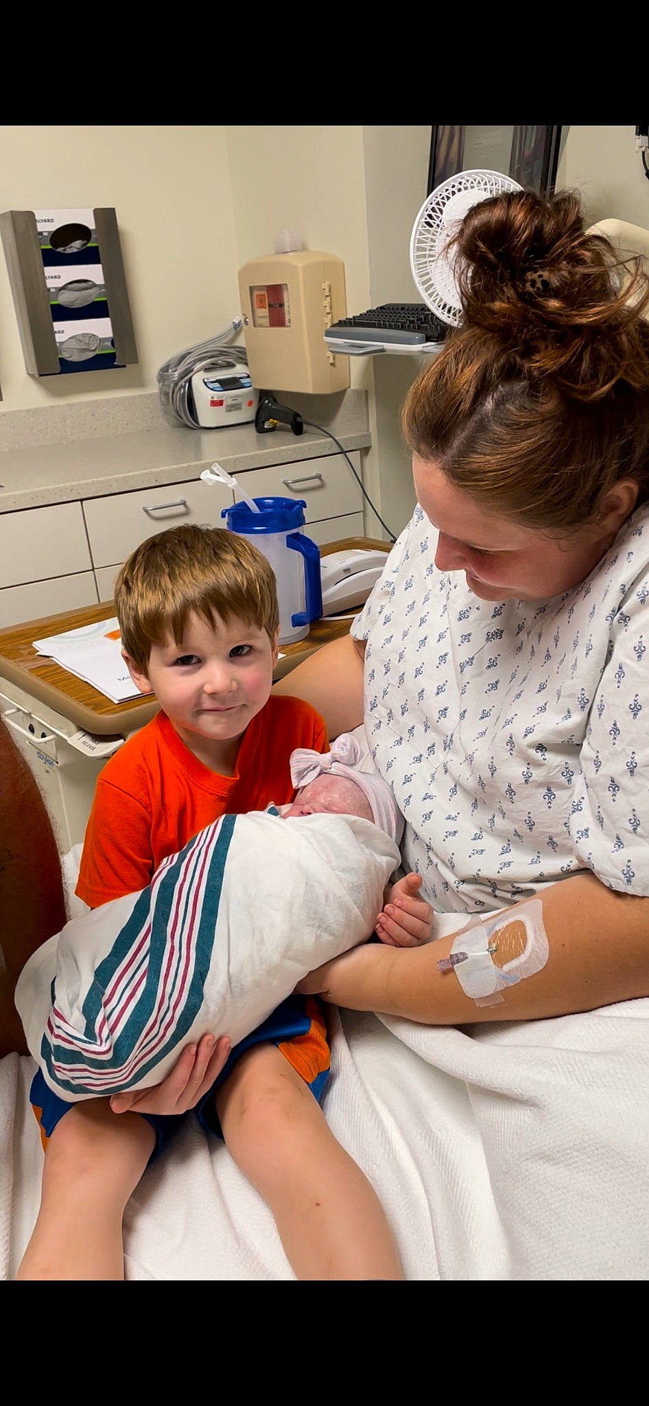 Leighton is registered to the contest to win money with this photo: arm, baby, child, comfort, event, hand, health_care, hospital, joy, kitchen_appliance, knee, lap, medical_procedure, patient, person, room, service, shorts, sitting, t_shirt