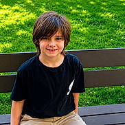 Adrien is registered to the contest to win money with this photo: child, boy, bench, grass, greenery, outdoor, smiling, casual_clothing, shorts, tshirt, daylight, park, nature, happy, portrait, person, sitting, youth, hair, face