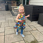 Octavia joined the competition — help win amazing prizes! child, girl, smiling, dress, floral_pattern, leggings, sneakers, outdoor, patio, stone_floor, furniture, brick_wall, happy, walking, daylight, curly_hair, playful, person, backyard, sunny