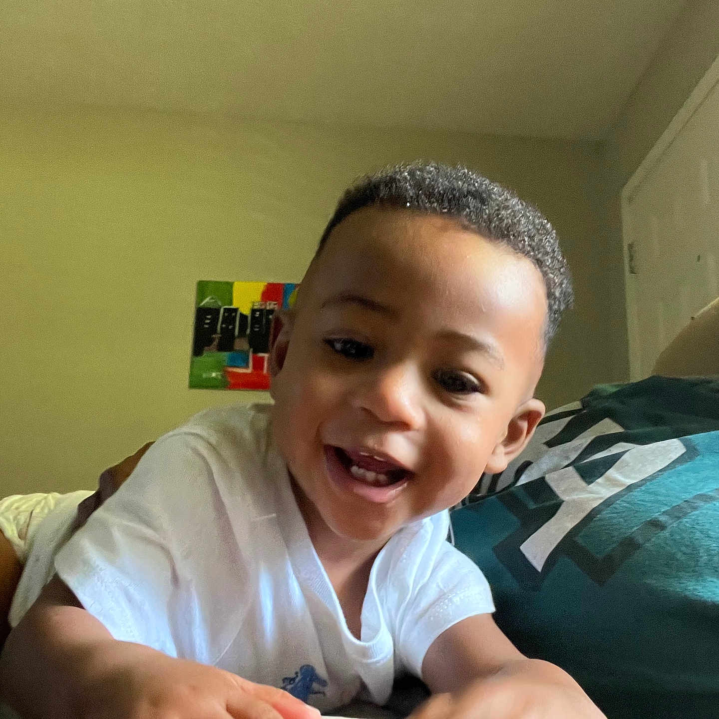 Tristen joined the competition — help win amazing prizes! casual, child, colorful, couch, curly_hair, expression, face, hand, happy, human, indoor, person, pillow, playful, portrait, smiling, toddler, wall_art, white_shirt, young_child