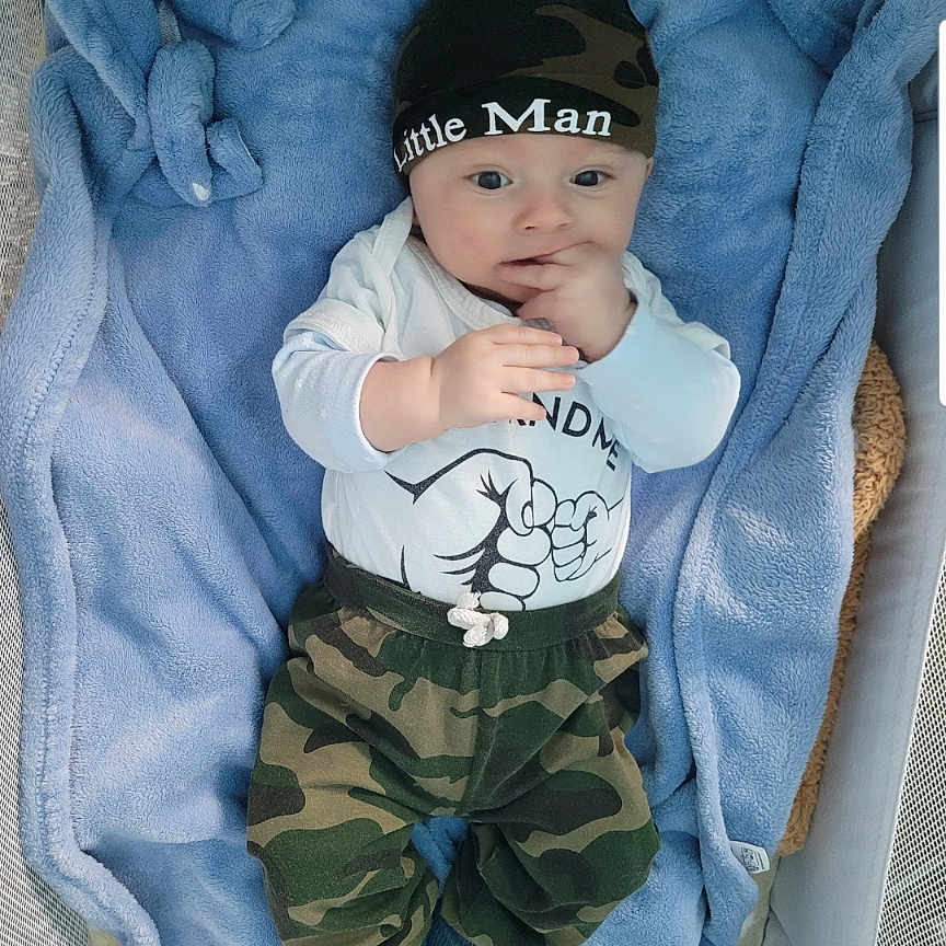 Bastien participe au concours pour gagner de l'argent avec cette photo : baby, baby_clothes, baby_hat, blanket, blue_blanket, camouflage_clothing, child, clothing, crib, cute, face, hand, hat, indoors, infant, lying_down, person, portrait, soft_texture, sucking_fingers