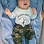 baby, beanie, blanket, blue_blanket, camouflage_pants, child, clothing, cute, daddy_and_me, fist_bump_graphic, happy, indoors, infant, little_man, lying_down, person, smiling, sock, soft_texture, white_shirt