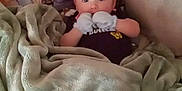 Scarlett is registered to the contest to win money with this photo: baby, blanket, mittens, couch, soft, comfort, infant, face, person, indoors, cozy, patterned_blanket, foot, resting, child, warm, cute, lying_down, home, portrait