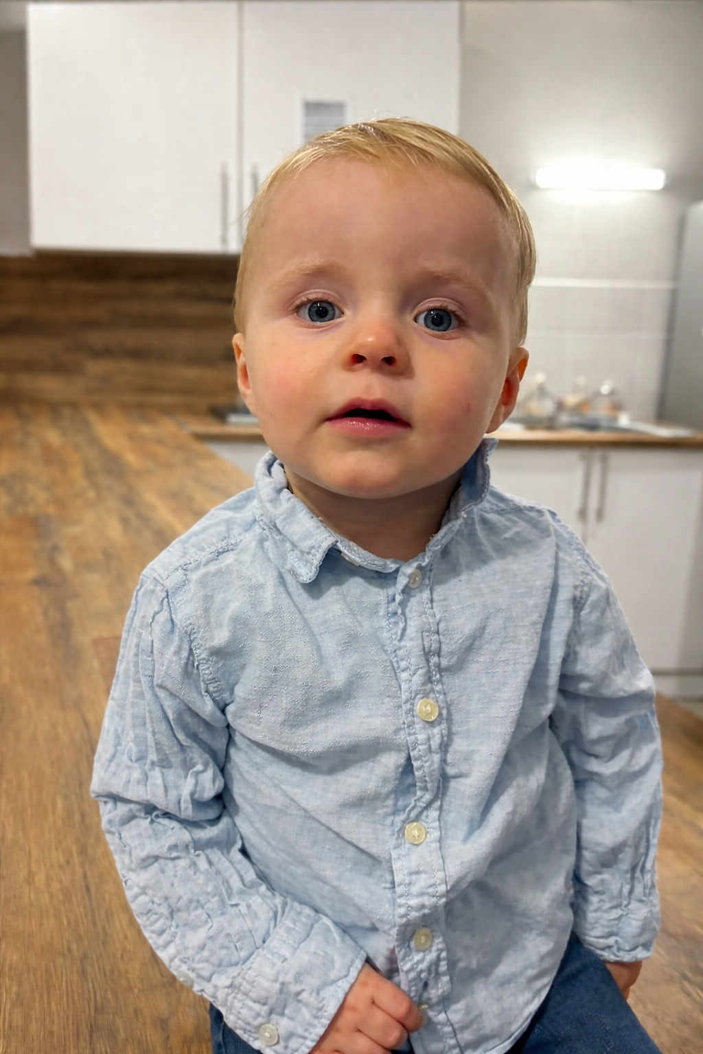 Lenny a rejoint le concours — aidez-le/la à gagner de superbes lots ! toddler, child, boy, blue_eyes, light_blue_shirt, indoor, kitchen, wooden_countertop, cabinet, curious, portrait, person, cute, young_child, standing, casual_clothing, modern_interior, expression, closeup, small_person