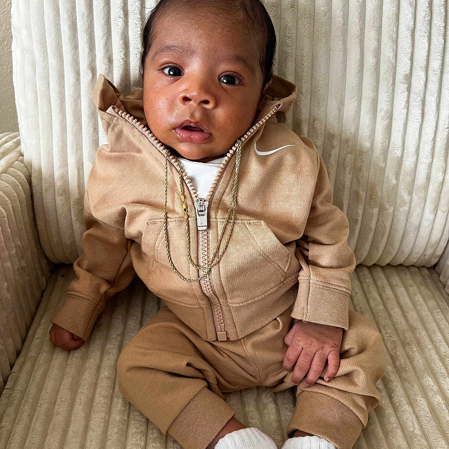 Tayden is registered to the contest to win money with this photo: armchair, baby, beige, child, clothing, cozy, cute, fashion, gold_chain, hoodie, indoor, infant, person, portrait, sitting, tan, texture, tracksuit, white_socks, young