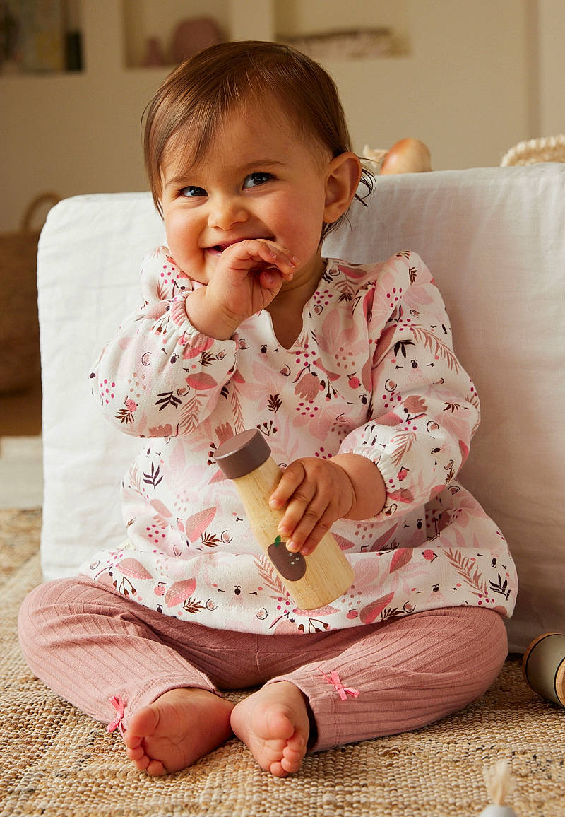 Mia a rejoint le concours — aidez-le/la à gagner de superbes lots ! baby, baby_toddler_clothing, cheek, child, comfort, face, finger, flooring, foot, happy, human_leg, joy, nightwear, pattern, person, pink, sitting, skin, sleeve, smile
