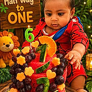 Anvith joined the competition — help win amazing prizes! baby, child, cake, fruit_cake, watermelon, grapes, orange_slice, birthday_candle, half_birthday, celebration, red_outfit, lion_plush, greenery, party, wooden_table, cute, curious, indoors, decorations, lighting