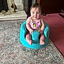 Isabella is registered to the contest to win money with this photo: baby, child, infant, blue_eyes, pink_clothing, turquoise_seat, indoor, carpet, rug, fireplace, brass_tools, home, cute, smiling, sitting, person, young_child, floor, comfort, portrait