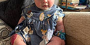 Isabella is registered to the contest to win money with this photo: baby, child, blue_dress, fairy_print, couch, beige, toy, wristband, curly_hair, wide_eyes, indoor, pillow, plush, sitting, cute, portrait, skin, foot, hand, furniture