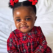 Khardiatou participe au concours pour gagner de l'argent avec cette photo : toddler, child, girl, red_bows, pigtails, plaid_dress, bed, white_bedspread, indoor, portrait, smiling, cute, young_child, curly_hair, red_clothing, holding_object, happy, person, baby, comfort