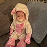 baby, child, infant, costume, sheep_costume, fluffy, pink, gingham, pacifier, mittens, booties, sitting, couch, pillow, crib, indoor, portrait, cute, cozy, smiling