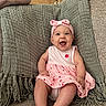 baby, infant, child, smiling, happy, portrait, sitting, indoors, couch, blanket, pink_dress, headband, bow, strawberry_pattern, textile, furniture, home, closeup, barefoot, photography