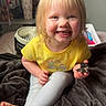 Sawyer is registered to the contest to win money with this photo: toddler, child, smiling, cookie, yellow_shirt, leggings, blanket, barefoot, indoor, fan, furniture, person, happy, face, hair, room, toy, background, sitting, cozy