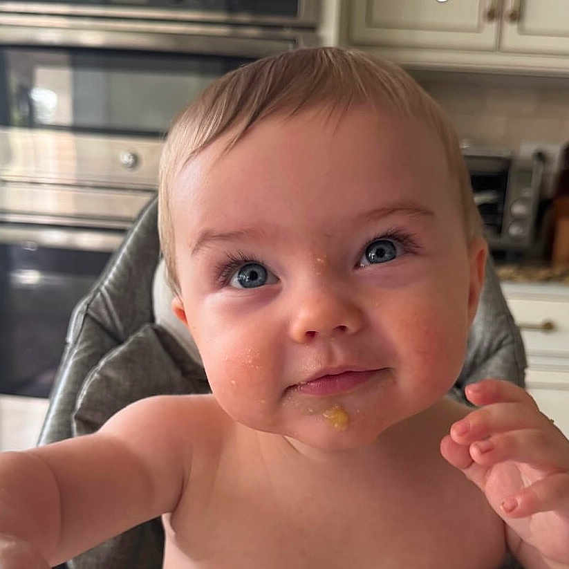 Everett is registered to the contest to win money with this photo: baby, blue_eyes, cheeks, child, closeup, curious, cute, expression, face, feeding, food_smear, high_chair, indoor, infant, kitchen, person, portrait, skin, smile, young_child