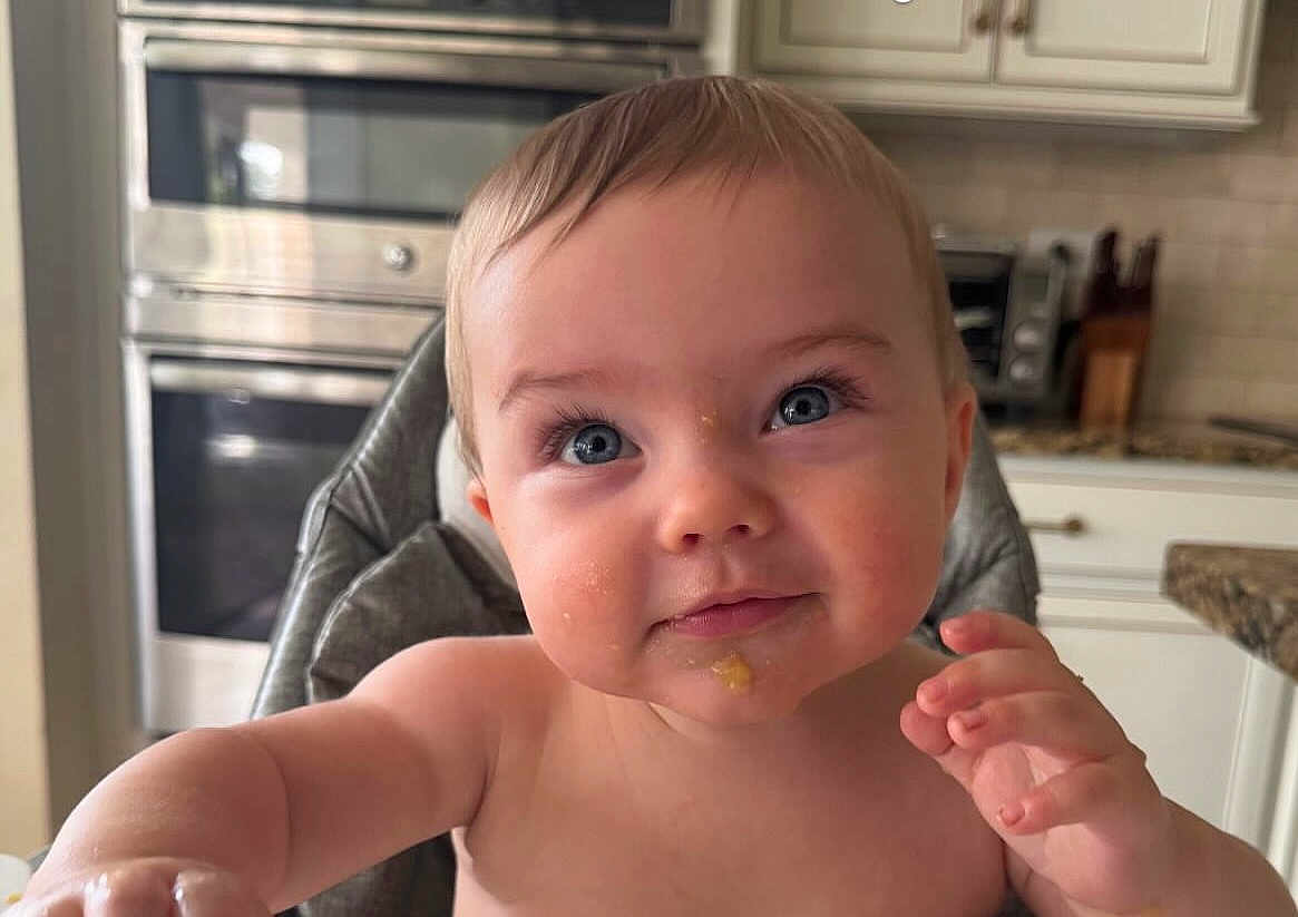Everett is registered to the contest to win money with this photo: baby, child, face, blue_eyes, high_chair, food_smear, kitchen, curious, cute, infant, portrait, indoor, skin, expression, closeup, person, young_child, feeding, smile, cheeks