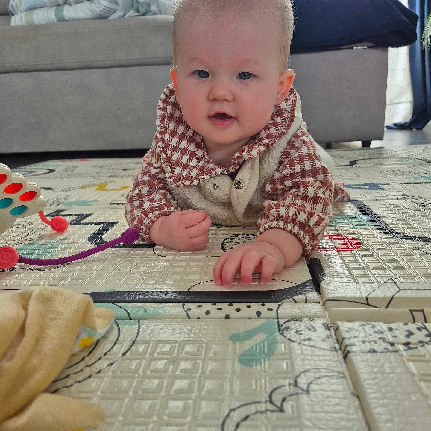 Maud participe au concours pour gagner de l'argent avec cette photo : baby, blanket, child, clothing, couch, curly_hair, dog, expression, face, floor, furniture, hand, home, indoor, infant, person, pet, play_mat, toy, window