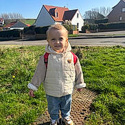 Lylio participe au concours pour gagner de l'argent avec cette photo : backpack, blue_sky, child, face, grass, house, jeans, kid, nature, portrait, puffer_jacket, road, roof, sidewalk, smile, sneakers, standing, suburban, sunlight, toddler