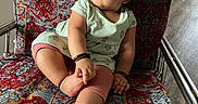 Naira is registered to the contest to win money with this photo: baby, child, sitting, chair, patterned_fabric, colorful, curly_hair, indoors, footwear_none, bracelet, mint_green, pink_leggings, expression_curious, metal_frame, floor, person, portrait, casual_clothing, cute, comfort