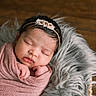 newborn, baby, sleeping, wrapped, blanket, pink, headband, flowers, fluffy, cushion, gray, wooden_floor, peaceful, portrait, indoors, cute, infant, resting, soft_texture, closeup