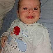 Abraham joined the competition — help win amazing prizes! baby, smiling, face, child, clothing, sweatshirt, bed, bedding, happy, infant, portrait, lying_down, cute, apparel, person, text_on_clothing, playful, indoors, fabric, young_child