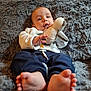 baby, child, stuffed_animal, toy, blanket, feet, face, hand, clothing, sweatshirt, pants, indoor, cozy, soft_texture, couch, portrait, cute, infant, relaxing, comfortable