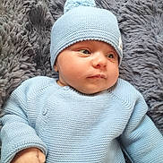 Tiago participe au concours pour gagner de l'argent avec cette photo : baby, infant, blue_hat, blue_sweater, knitwear, blanket, fluffy, soft_texture, cute, child, newborn, portrait, indoor, small_hand, face, curious, lying_down, warm_clothing, cozy, resting