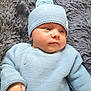 baby, infant, blue_hat, blue_sweater, knitwear, blanket, fluffy, soft_texture, cute, child, newborn, portrait, indoor, small_hand, face, curious, lying_down, warm_clothing, cozy, resting