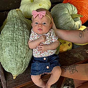 Maycie is registered to the contest to win money with this photo: baby, child, girl, bow, headband, denim_skirt, pumpkin, gourd, bench, tattoo, arm, footwear, outdoor, wood, nature, fall, cute, portrait, person, sitting