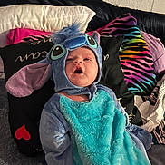 Harper is registered to the contest to win money with this photo: baby, costume, blue, pillow, blanket, couch, indoor, child, cute, plush, face, person, clothing, soft, seated, young, expression, colorful, fabric, headwear