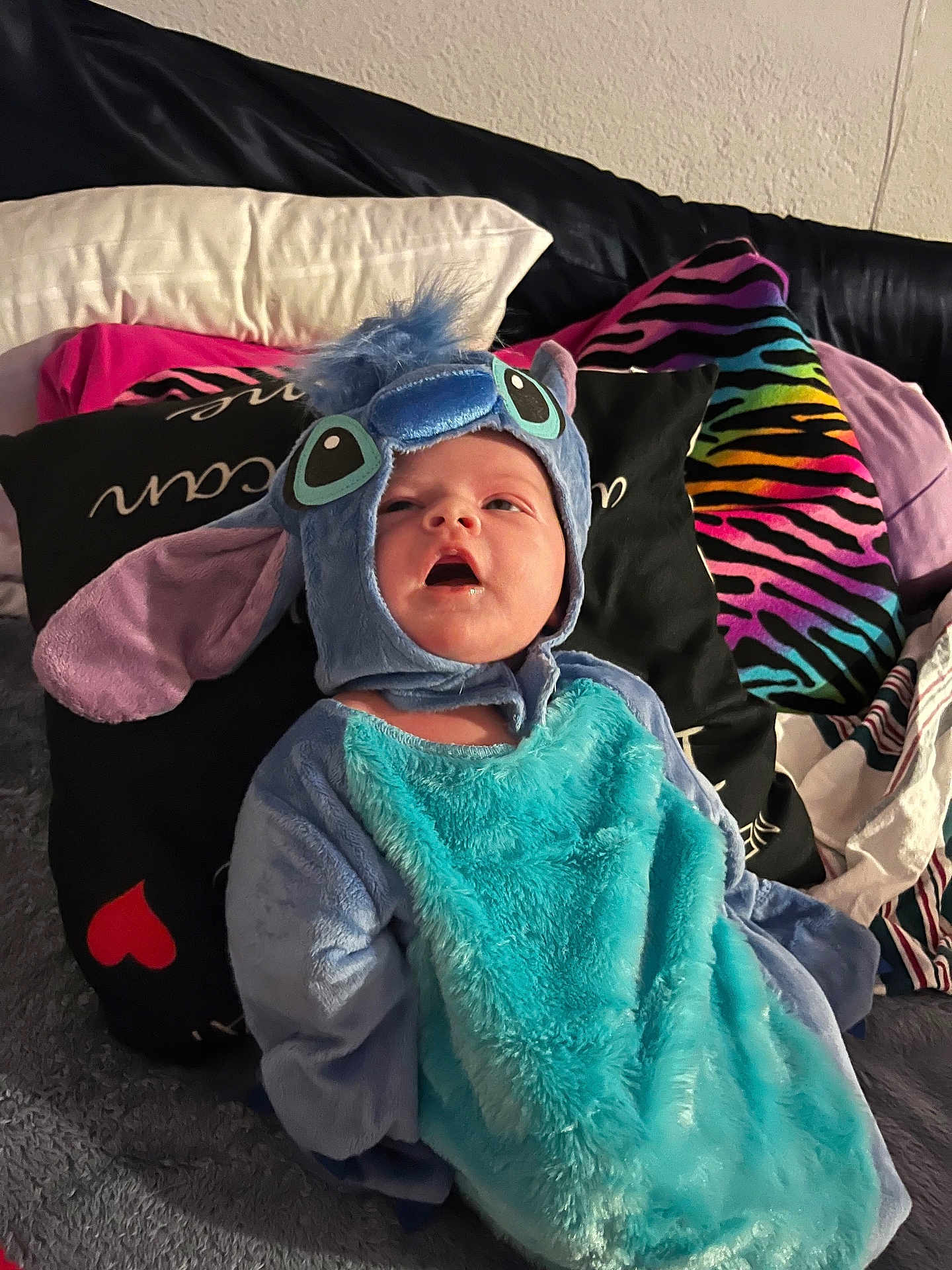 Harper is registered to the contest to win money with this photo: baby, costume, blue, pillow, blanket, couch, indoor, child, cute, plush, face, person, clothing, soft, seated, young, expression, colorful, fabric, headwear