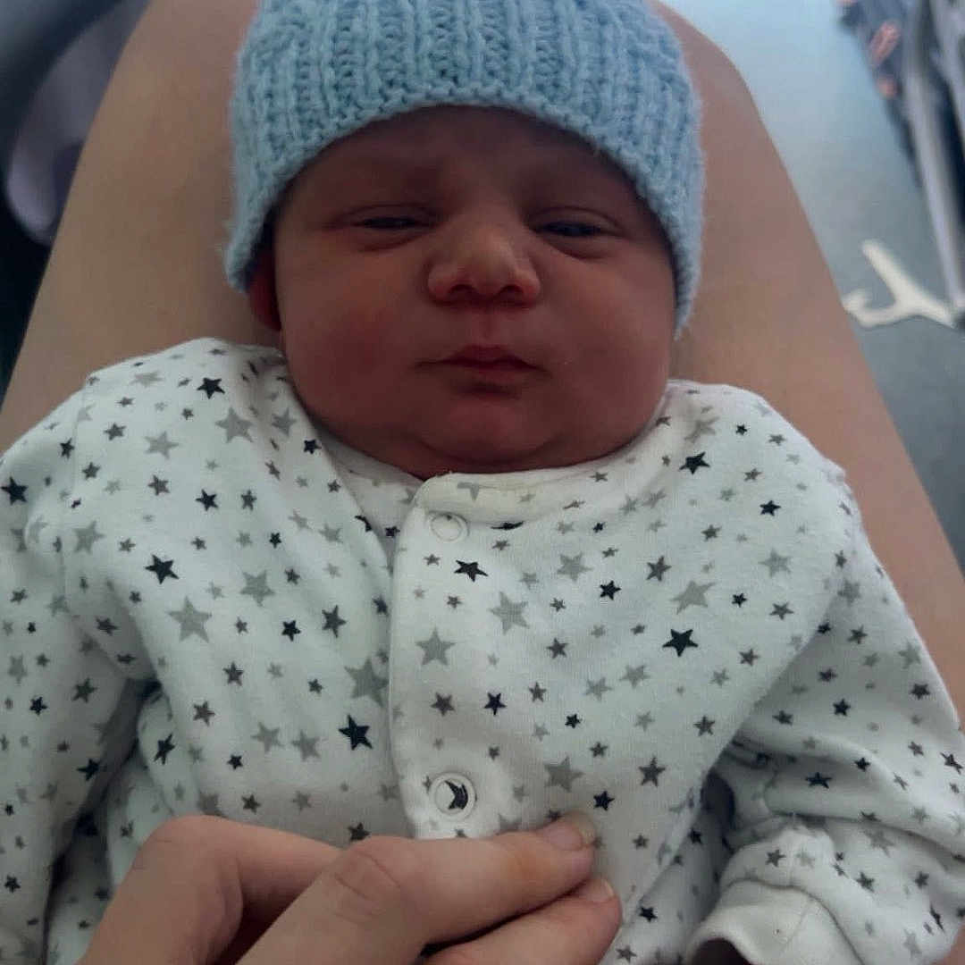 Jamelle is registered to the contest to win money with this photo: baby, bedroom, closeup, clothing, cute, fingers, hand, human, indoor, infant, knit_hat, legs, newborn, pajamas, person, sitting, skin, small, soft_light, stars_pattern