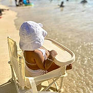 Aurora is registered to the contest to win money with this photo: baby, beach, chair, child, hat, holiday, ocean, outdoor, relaxation, sand, sea, sitting, small_person, summer, sunhat, sunlight, swimwear, vacation, water, waves